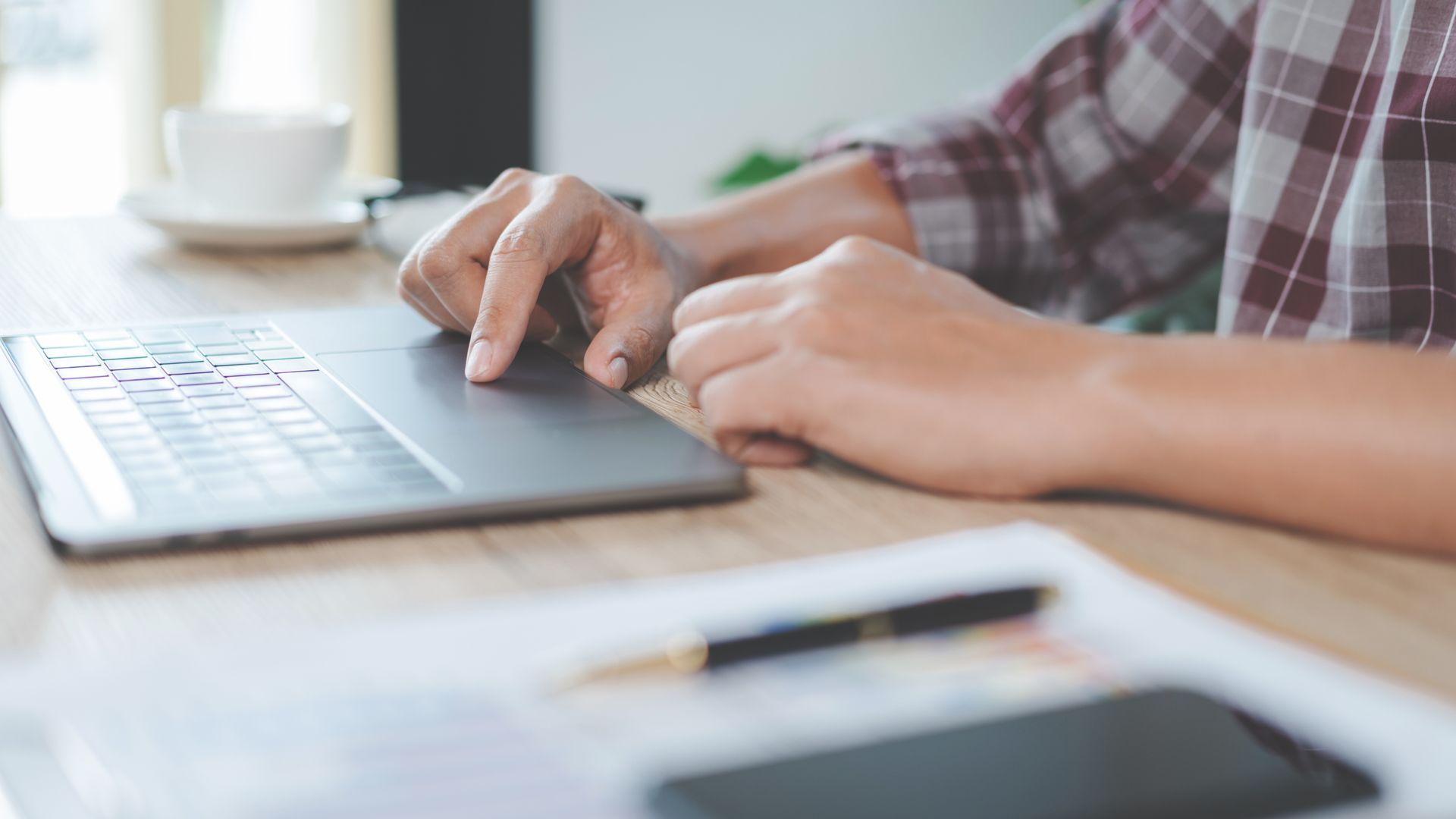 A close-up of a man stamping a mark on a financial report with a laptop besides him. A close-up of a man stamping a mark on a financial report with a laptop besides him.