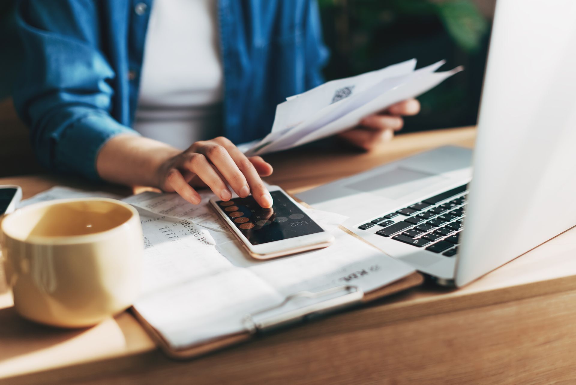Businesswoman using a calculator and laptop to keep track of her business accounting.