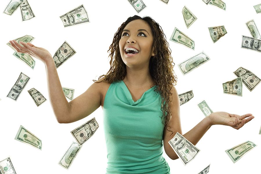Woman with arms outstretched, smiling, as money falls around her.