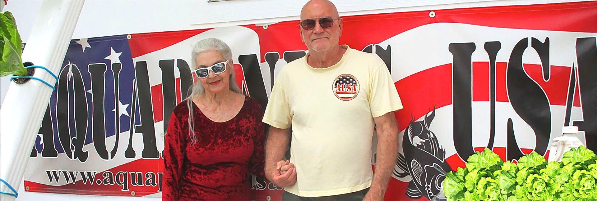 A couple stands in front of a banner with a USA flag design.