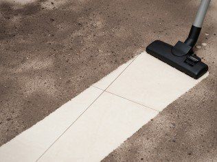 A vacuum cleaner is being used to clean a tiled floor.
