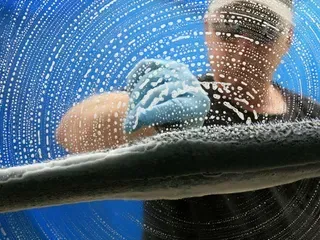 A man is cleaning a window with a cloth.
