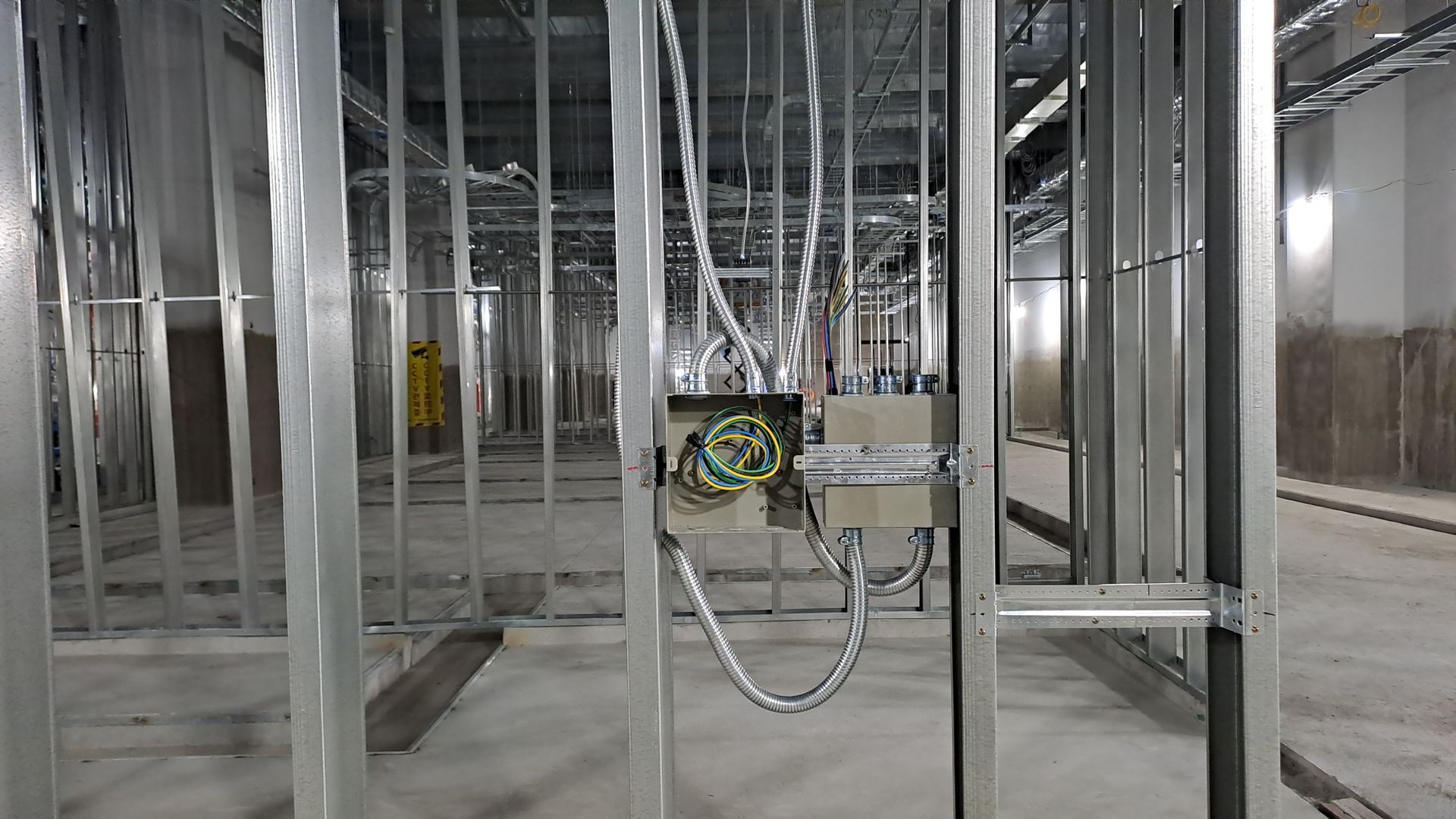Construction site with a crane and partially built concrete structure behind a tan barrier