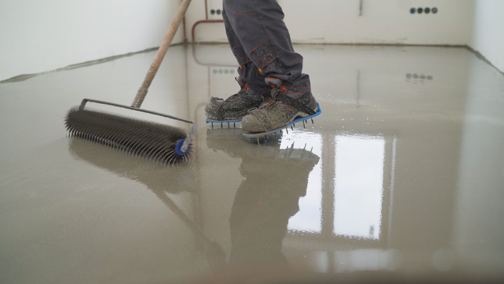 Person smoothing a glossy wet floor with a squeegee in a bright room.