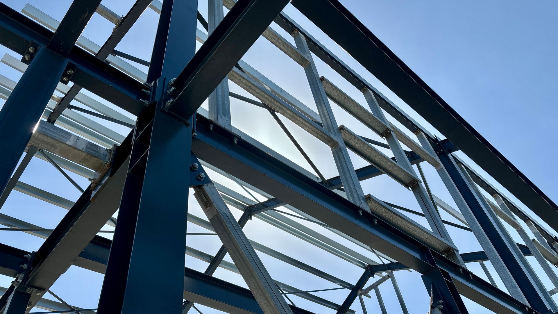 Construction worker on wooden house framing under a bright blue sky