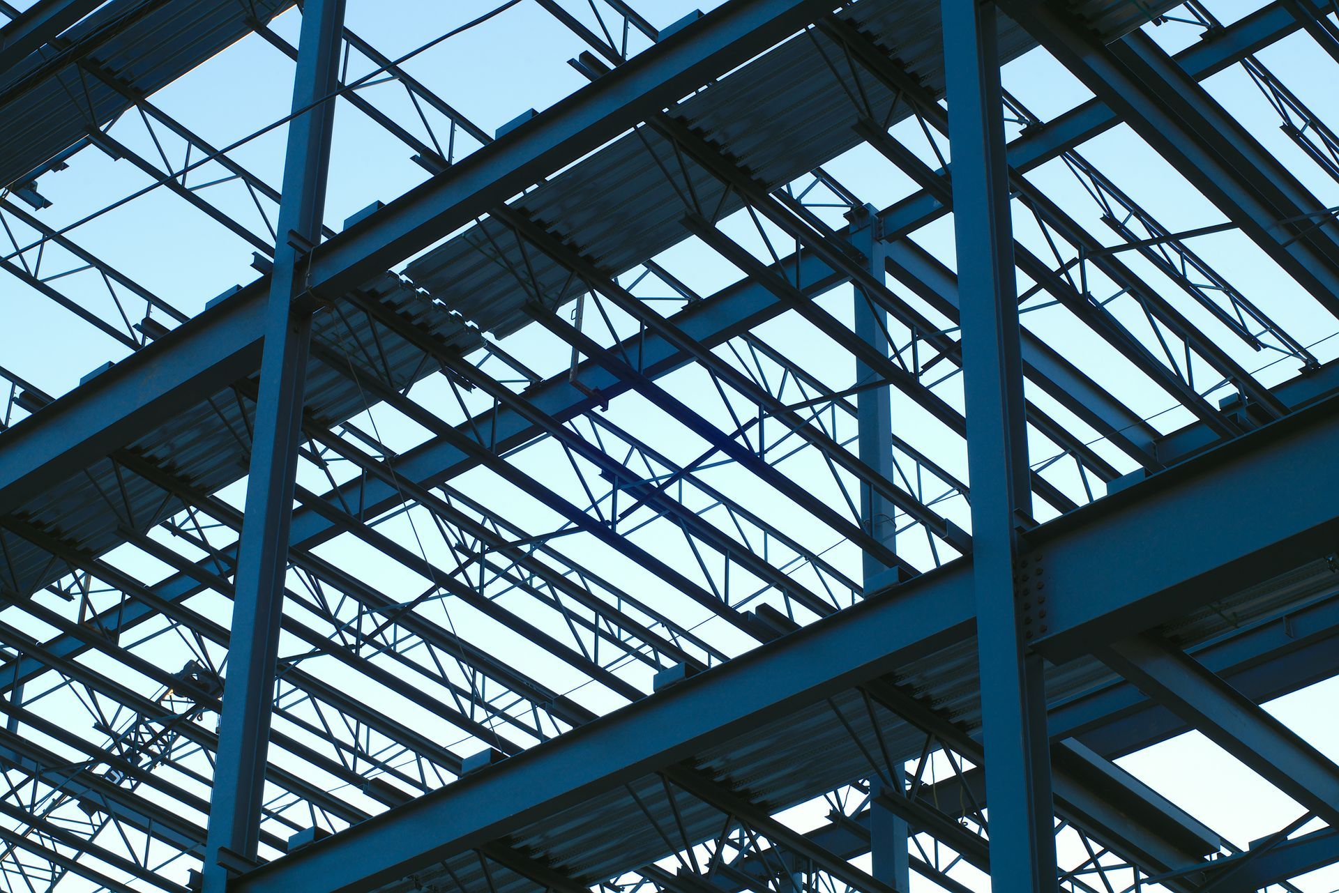 Worker in a blue hard hat installing a ceiling beam inside a house under construction