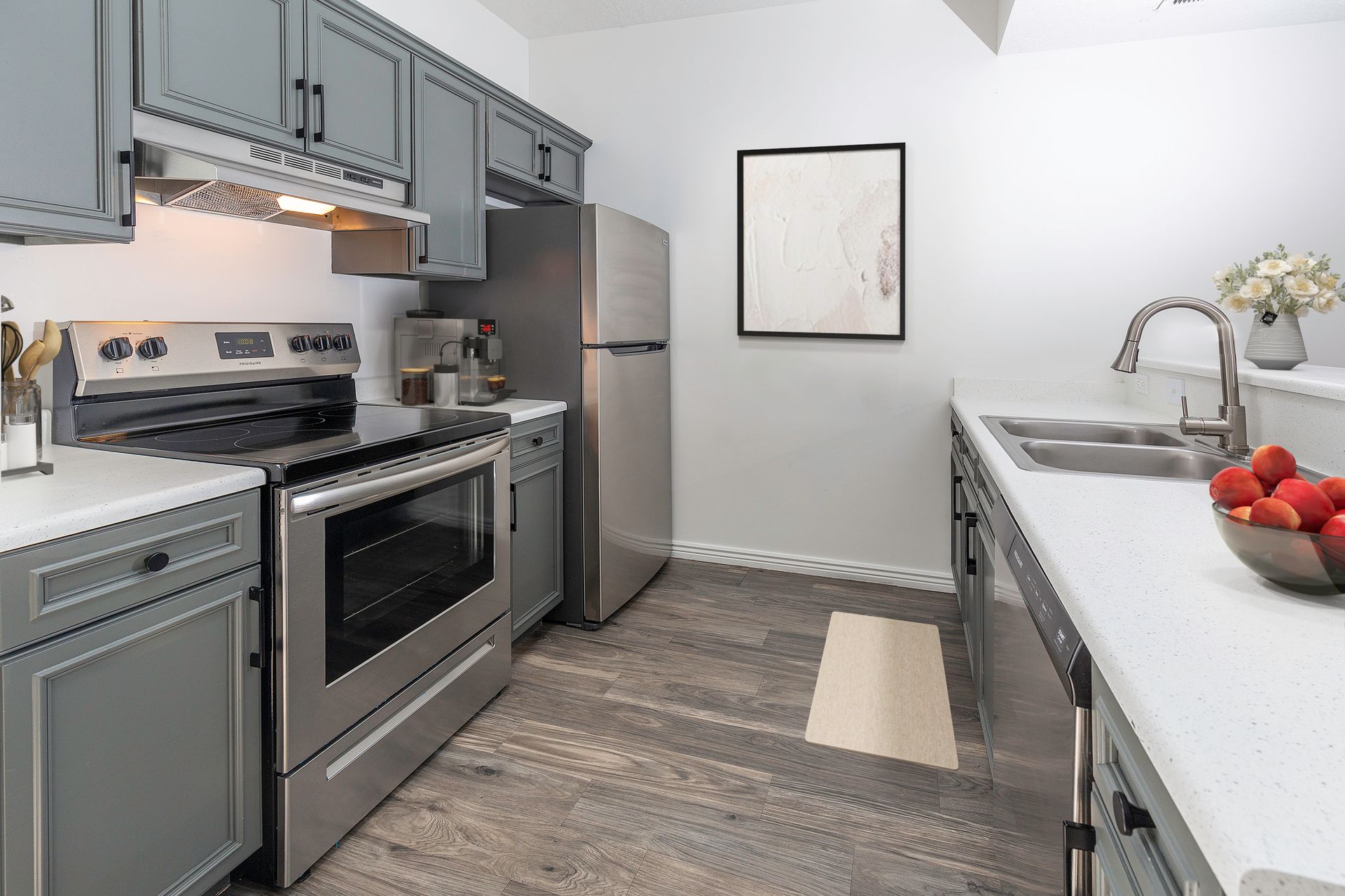 Modern kitchen with stainless steel appliances, gray cabinets, and white countertops.