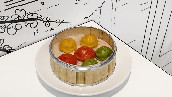 Round wooden container of colorful tomatoes on a white plate in a kitchen setting
