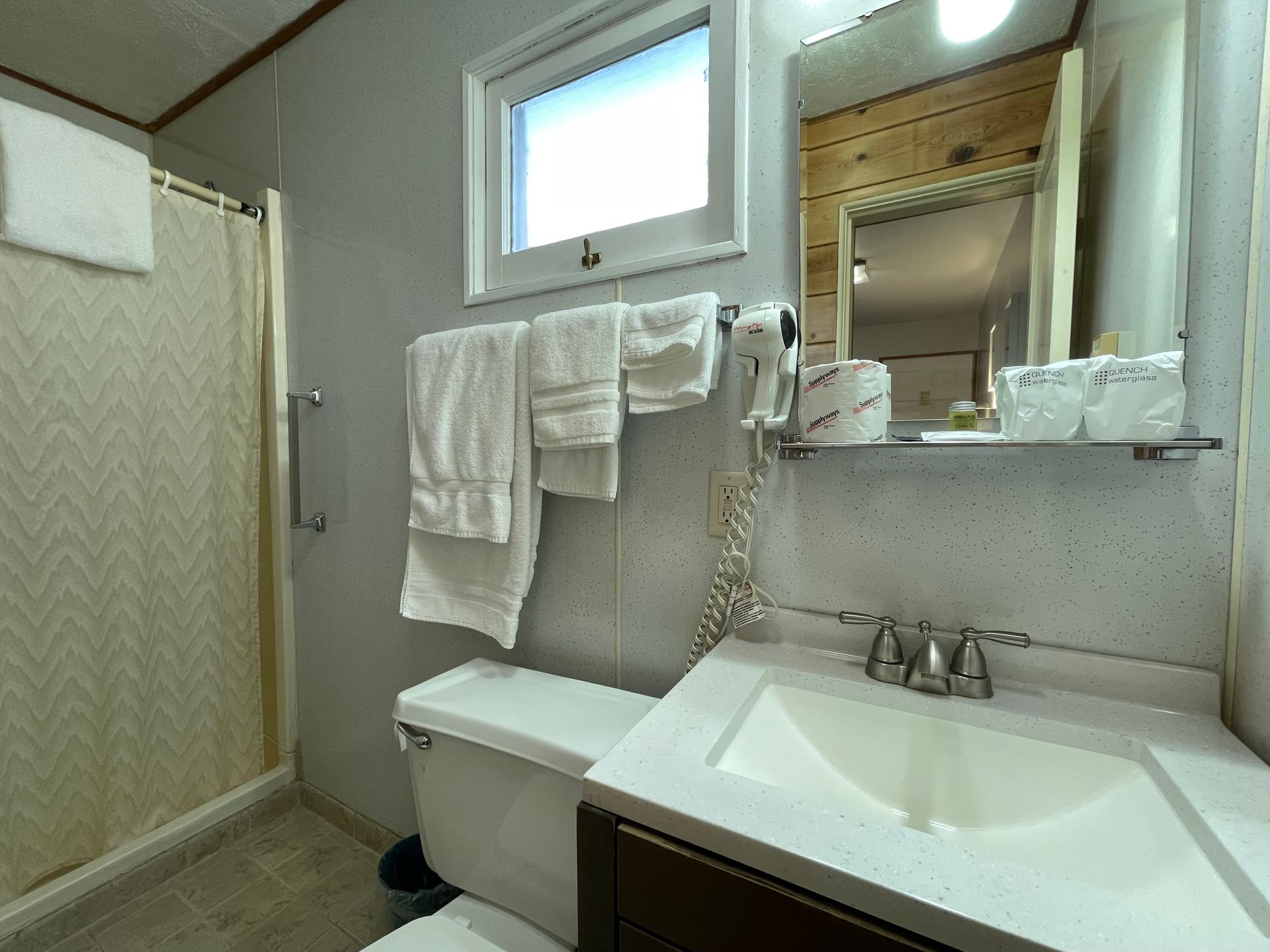A bathroom with a sink , toilet , shower and mirror.