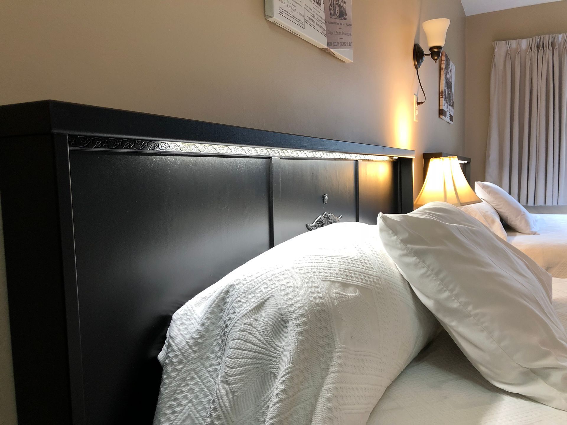 A bed with white sheets and pillows in a hotel room
