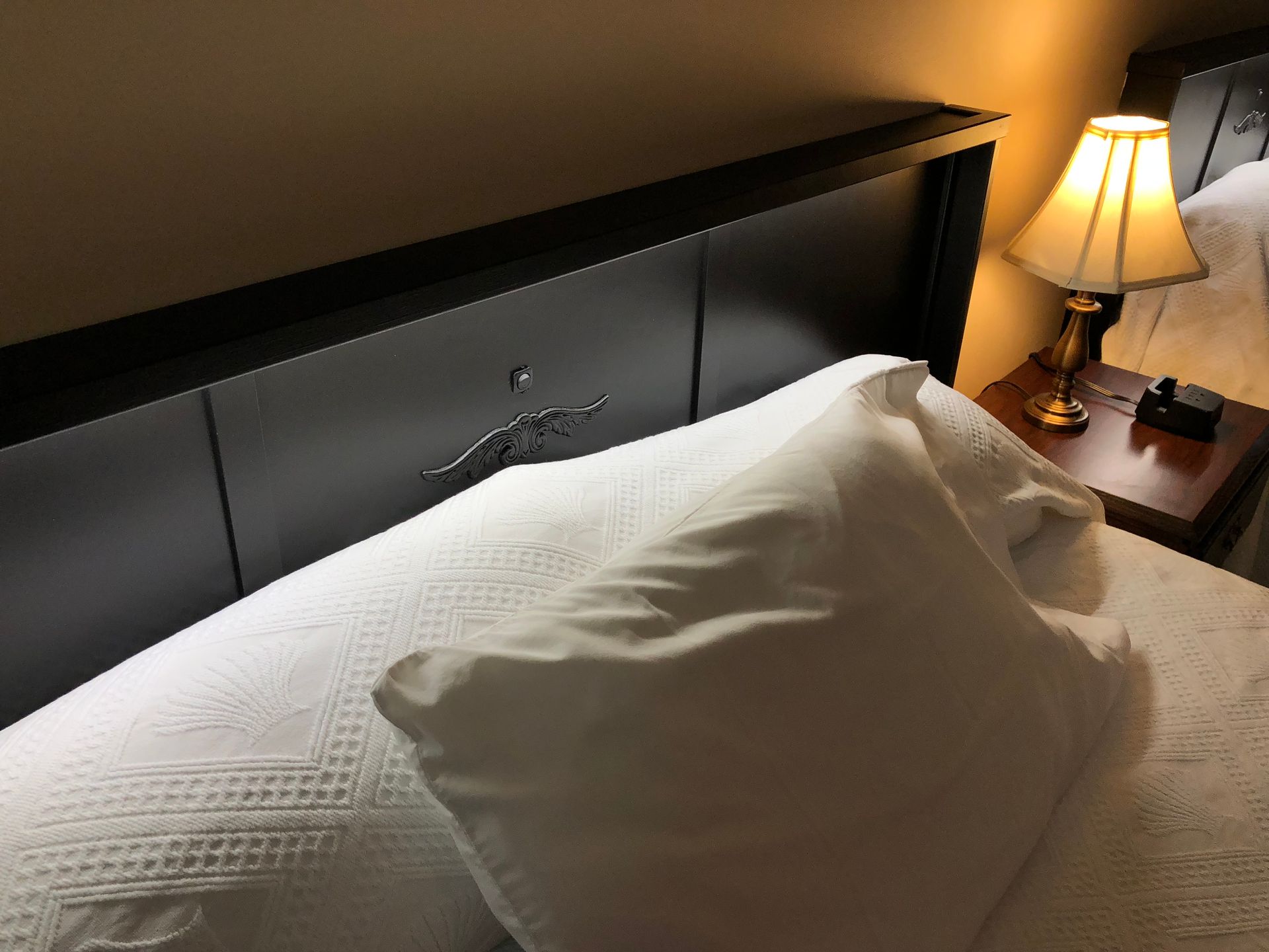 A bed with a lamp on the nightstand next to it