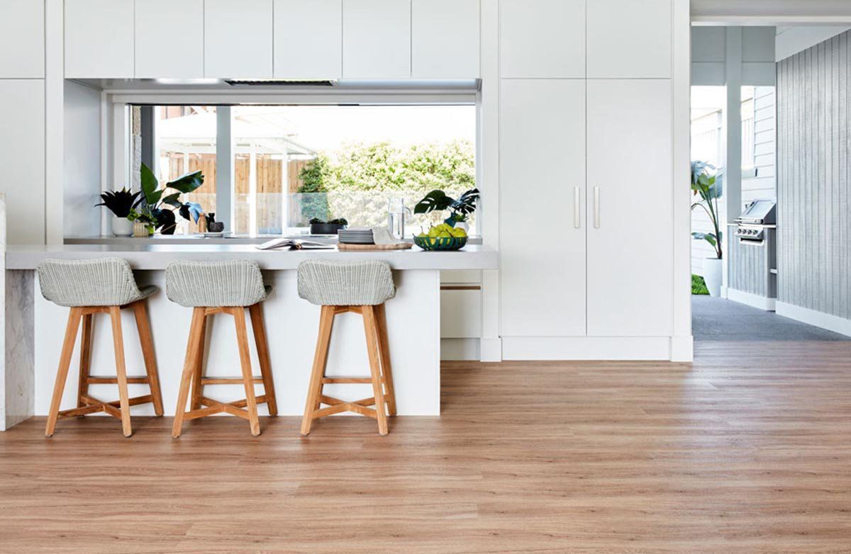A Kitchen with White Cabinets, Wooden Floors, and Stools — Kelwin Coastal Carpets In Kundra Park, QLD