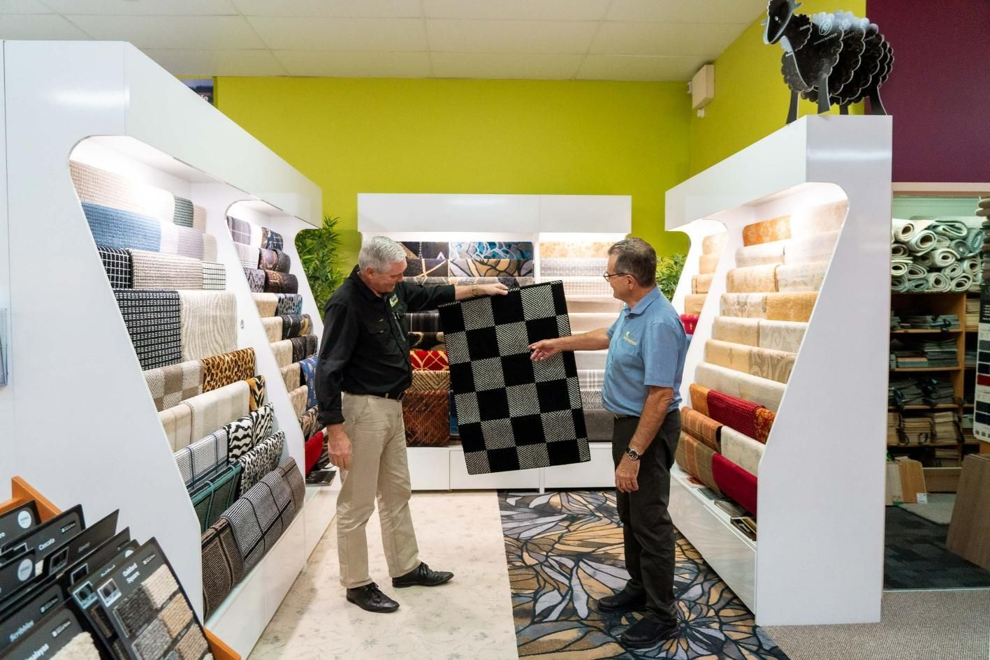 Two Men Are Looking at A Rug in A Store — Kelwin Coastal Carpets In Kundra Park, QLD