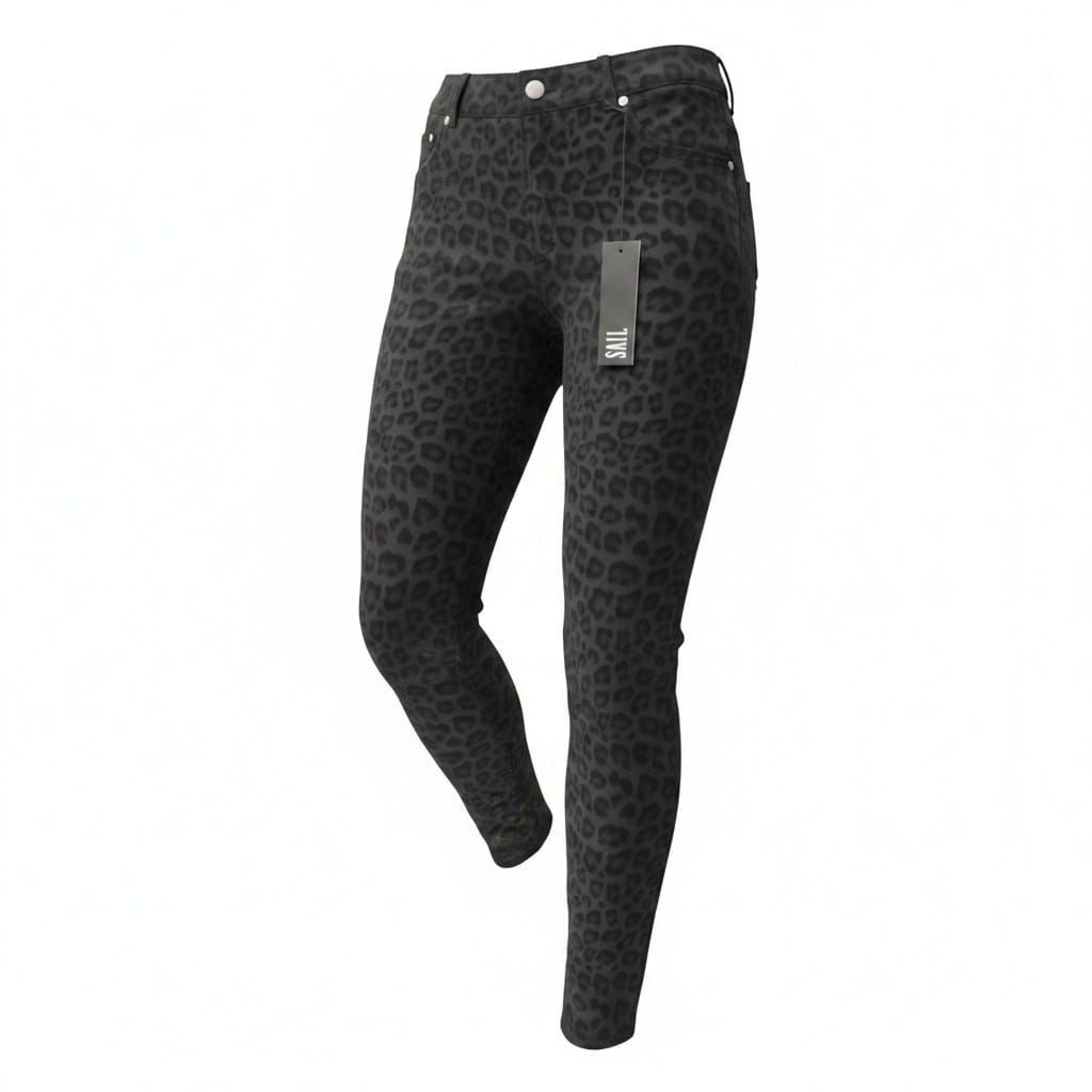 Mujer con blusa negra y pantalones estampados de pie contra una pared lisa.