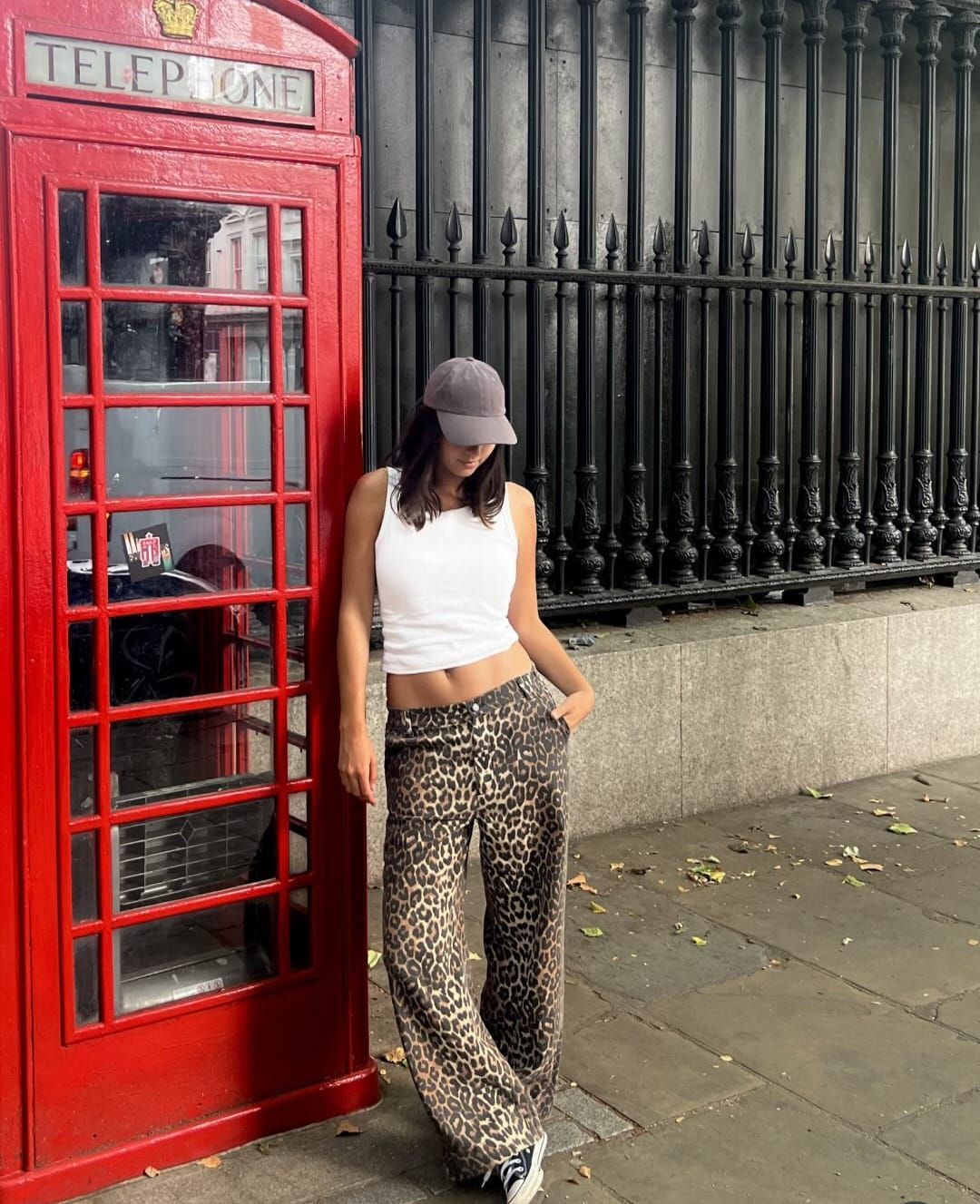 Falda con estampado de leopardo y top negro con zapatillas blancas sobre pavimento gris, vista desde arriba.