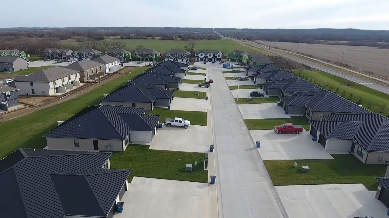 Aerial view of a suburban neighborhood with rows of houses, driveways, and a central street.