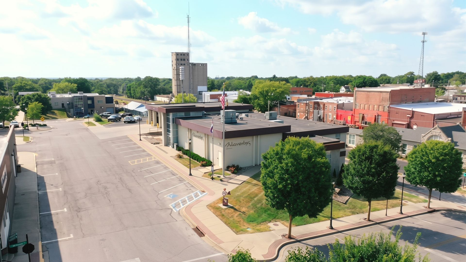 Downtown street with low buildings, trees, and a tall tower under a clear sky