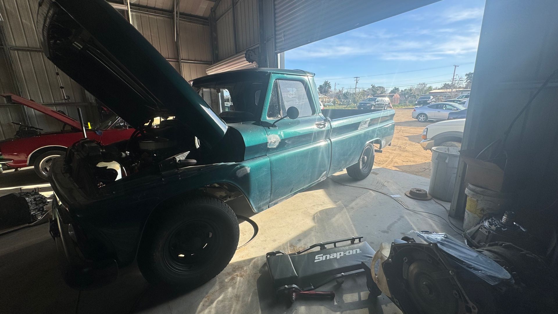 Green vintage pickup truck in a garage, hood open, engine parts visible. | Alberto's Transmissions & Auto
