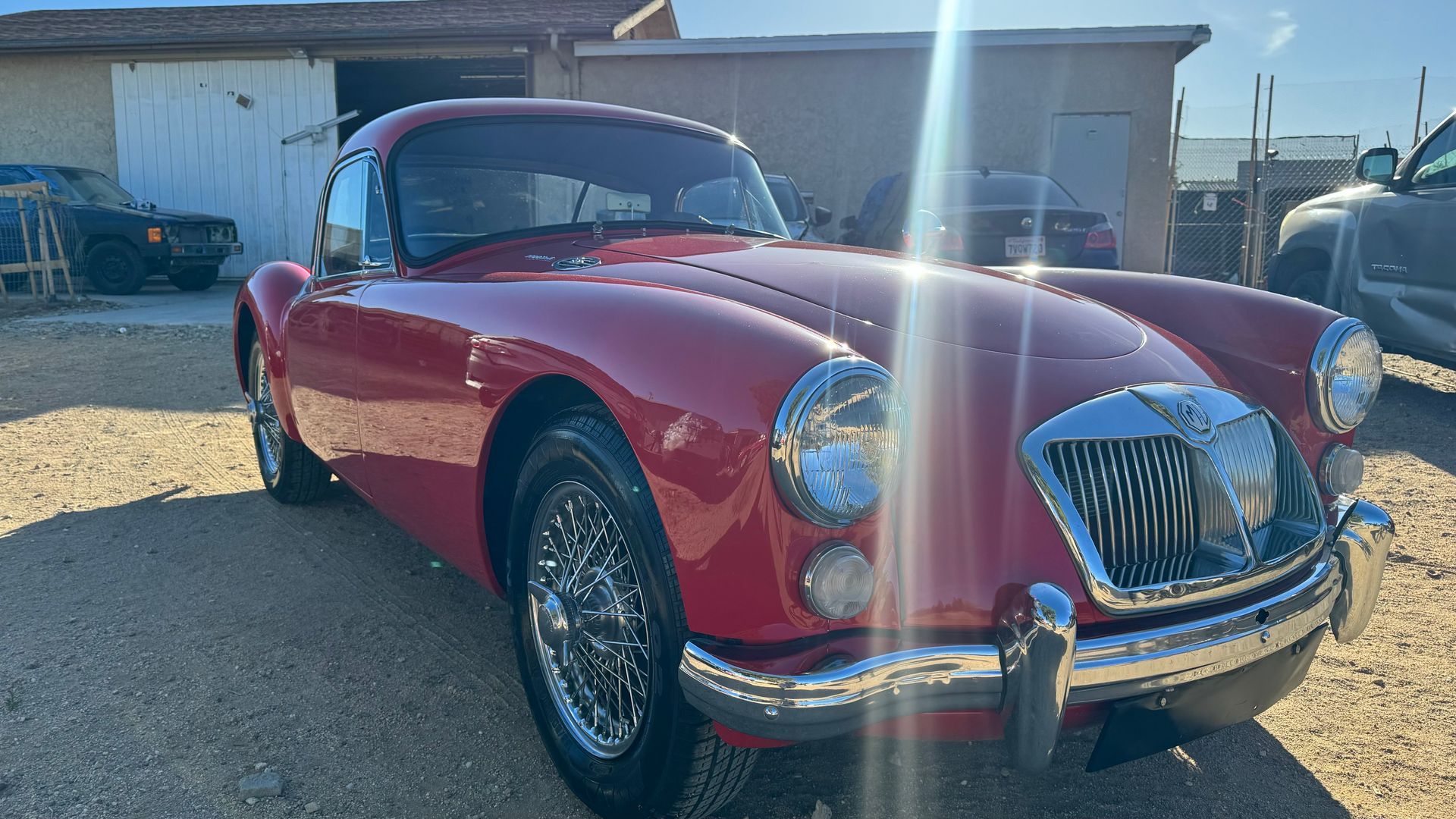 Red classic MGA car parked outdoors, shiny chrome accents, sunny day. | Alberto's Transmissions & Auto