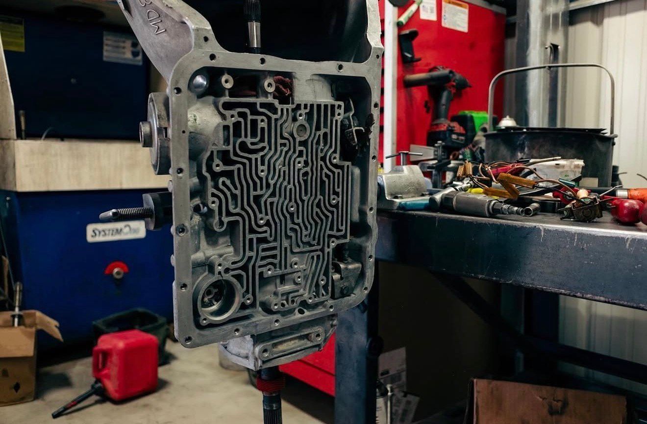 Open transmission valve body on stand, showing intricate channels in a shop. | Alberto's Transmissions & Auto