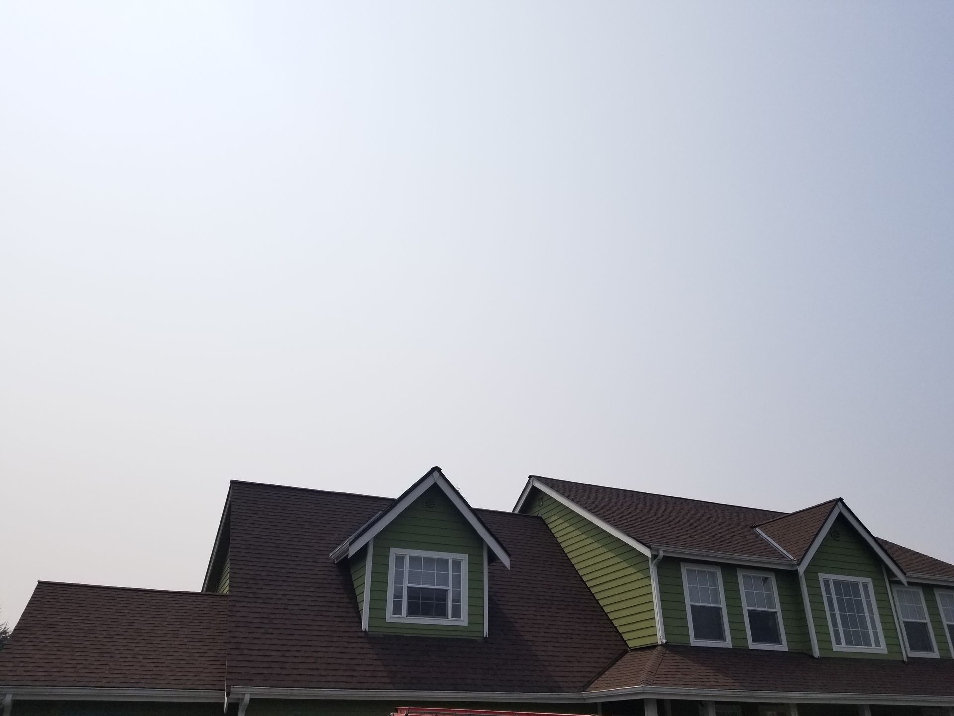 Rooflines and dormer windows of a house against a pale evening sky
