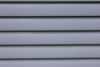 Close-up of light gray horizontal metal siding panels with thin shadows between rows