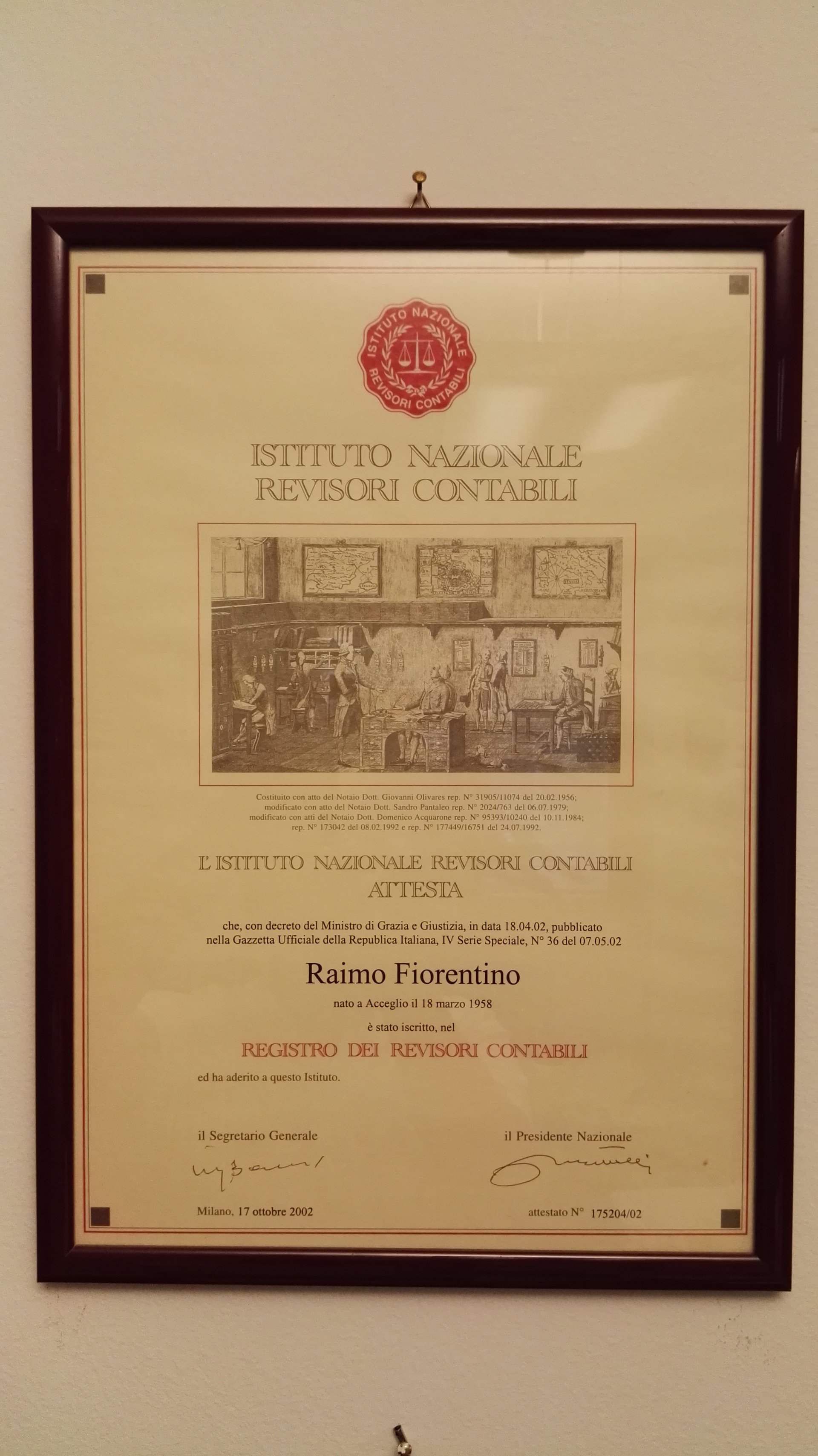 Certificato incorniciato con sigillo rosso e testo centrato, appeso a una parete.
