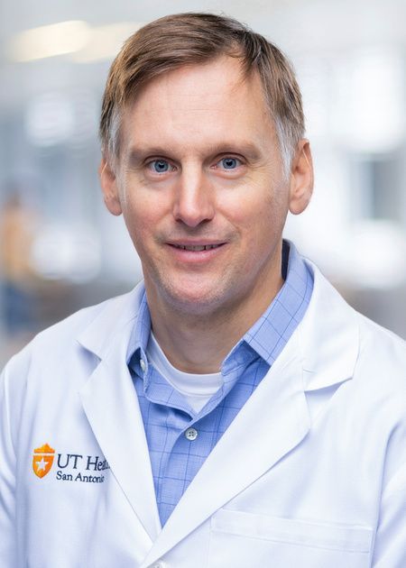 A man in a white lab coat is smiling for the camera.