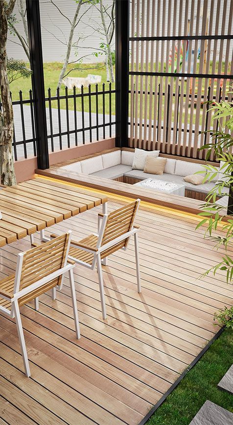 Modern outdoor deck with two wooden chairs, a low cushioned seating nook, and black railing views of greenery
