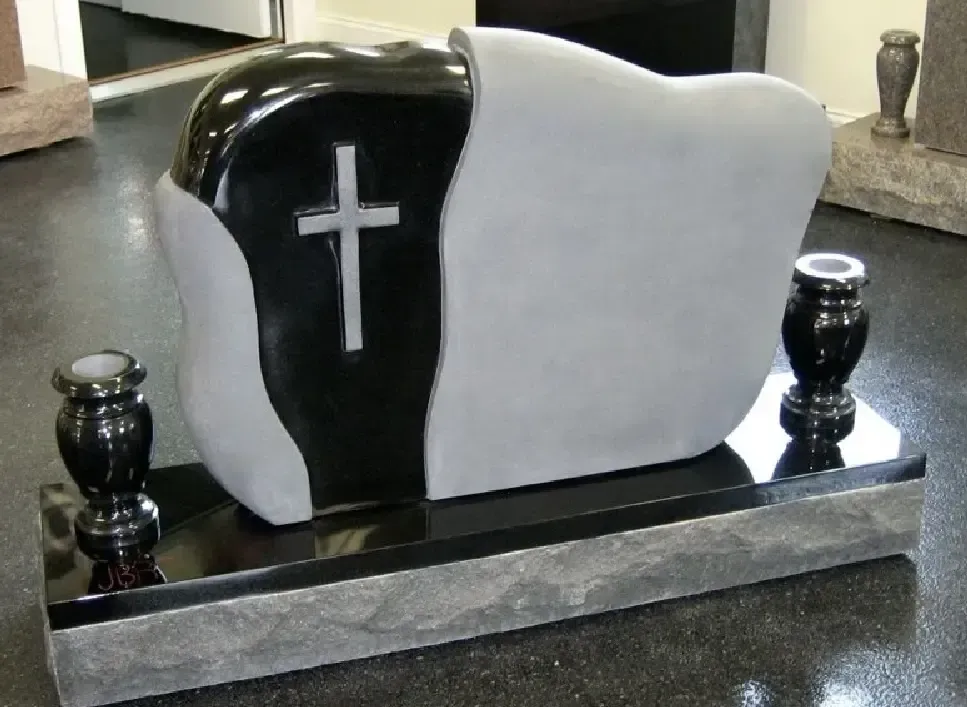 Monument with black and gray stone, cross, vases, and a black base.