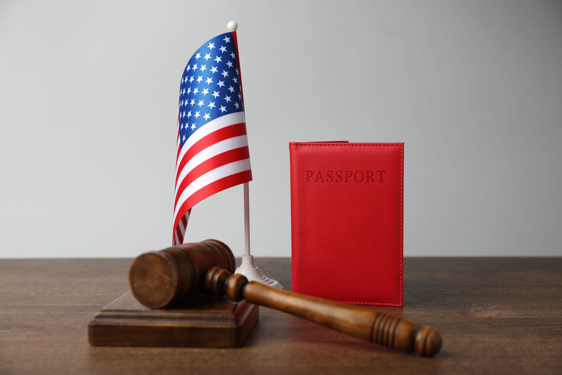 U.S. flag, red passport, and judge's gavel on a wooden table