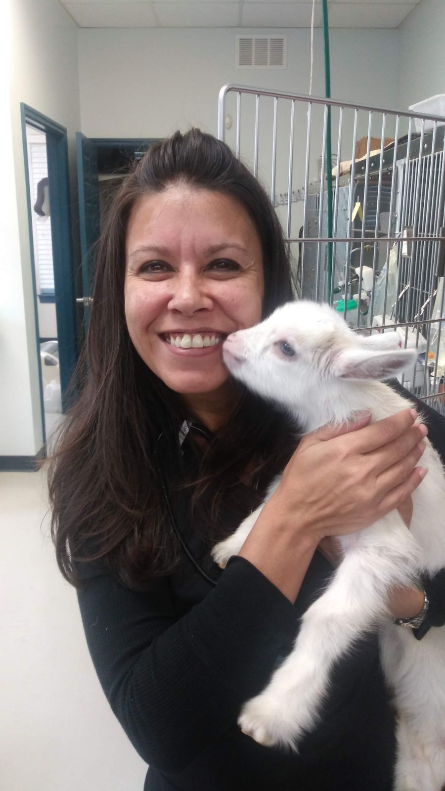Woman smiling and holding a small white dog indoors