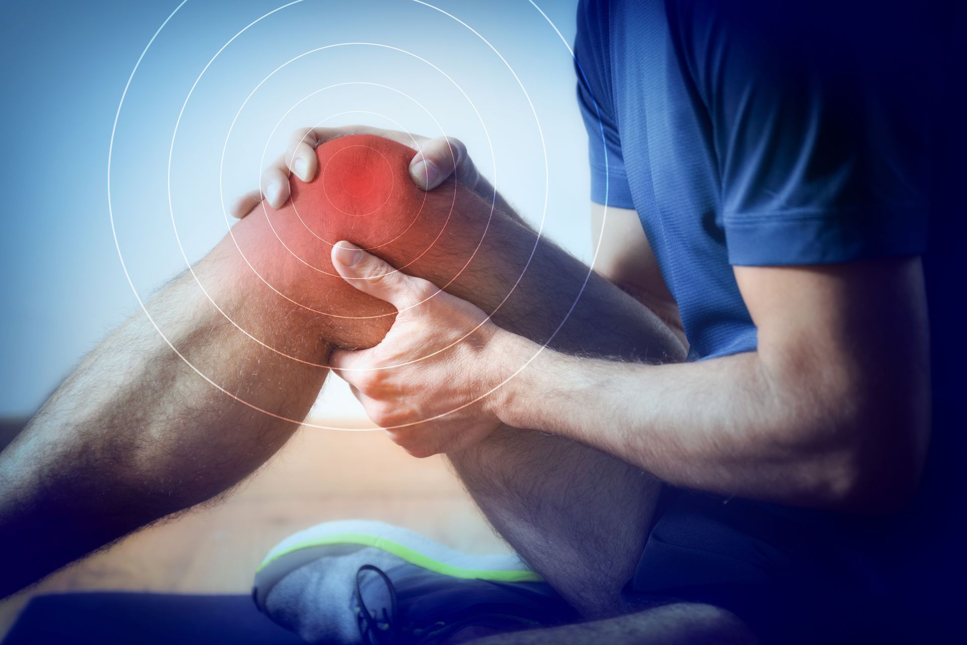 Person holding a painful red knee with blue medical overlay on a therapy table