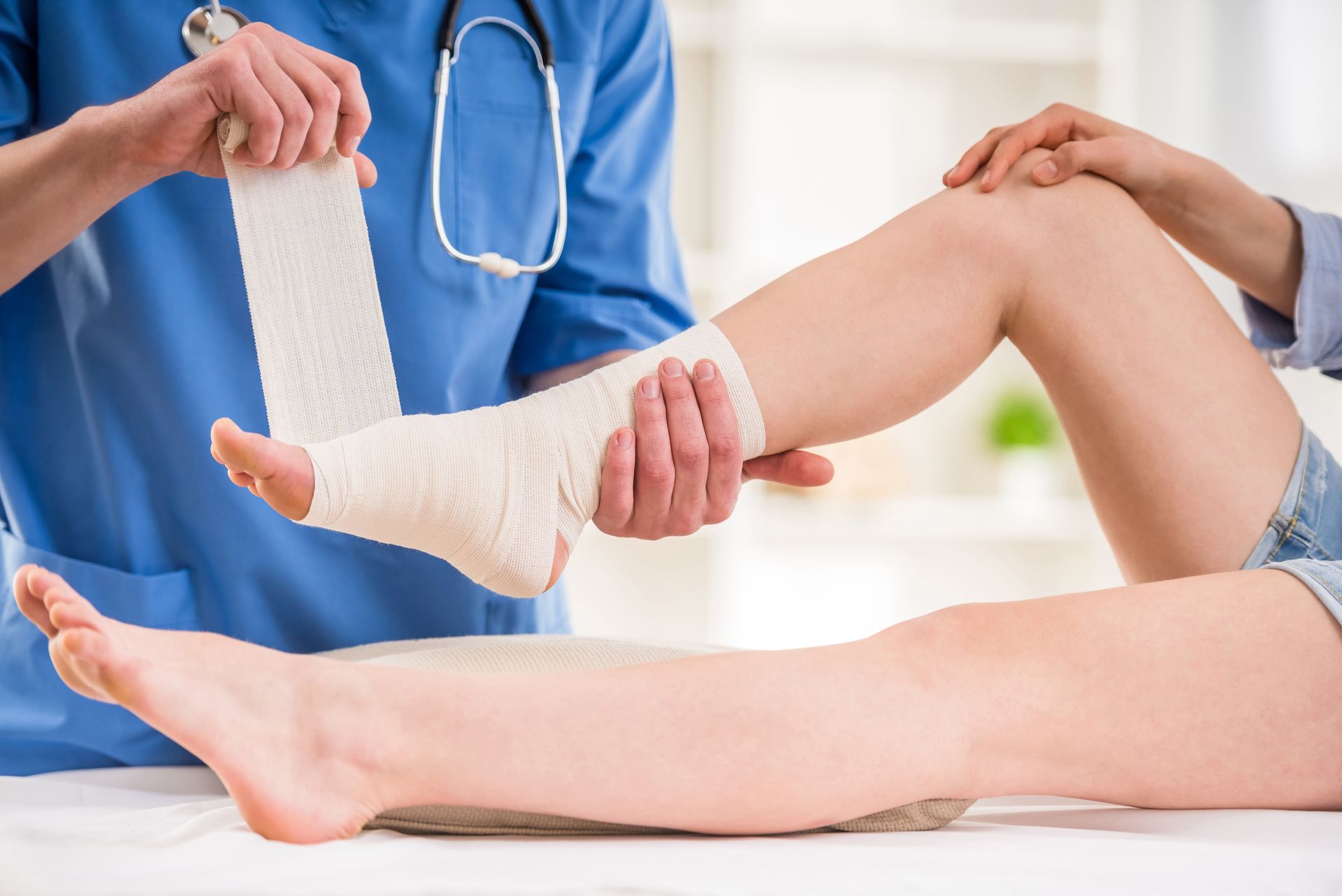 Medical professional wrapping a patient’s lower leg with a white bandage in a clinic