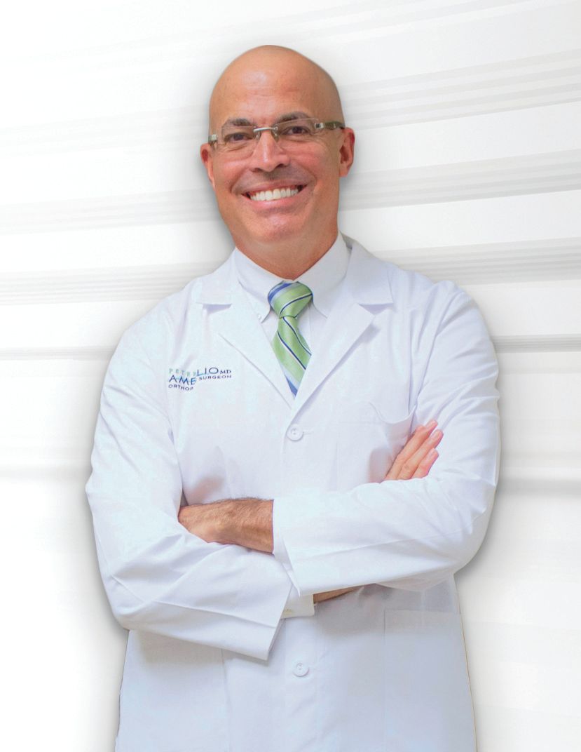Smiling doctor in white coat with arms crossed against a light background