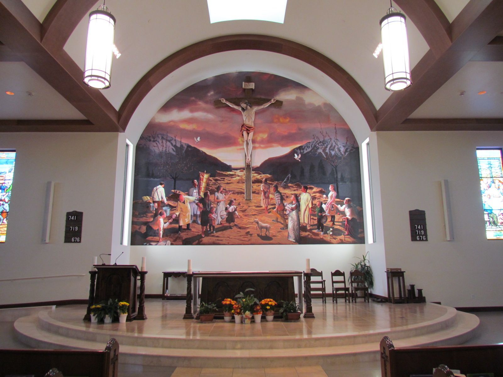 Church sanctuary with altar, floral arrangement, and large mural backdrop under arched ceiling