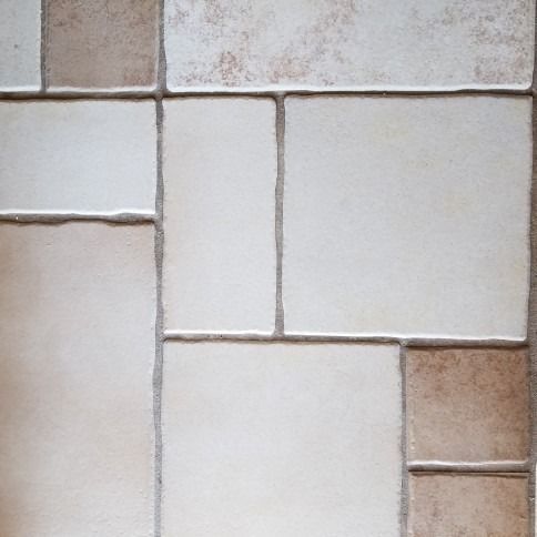 Close-up of beige and white ceramic tiles arranged in a grid pattern.