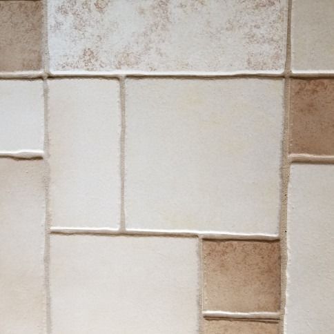 Close-up of beige and white tiled wall with worn grout lines