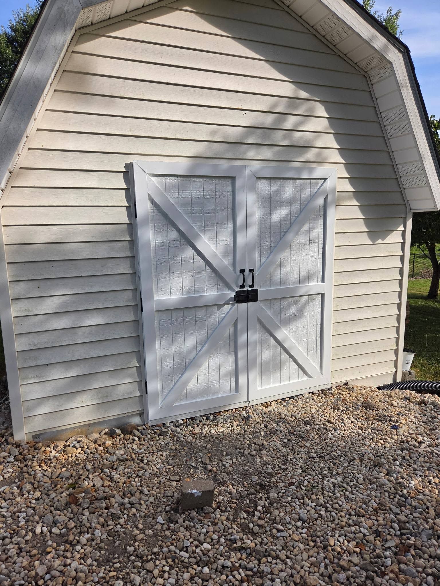 White shed with double doors and black latch, numbered 11, on a gravel yard.