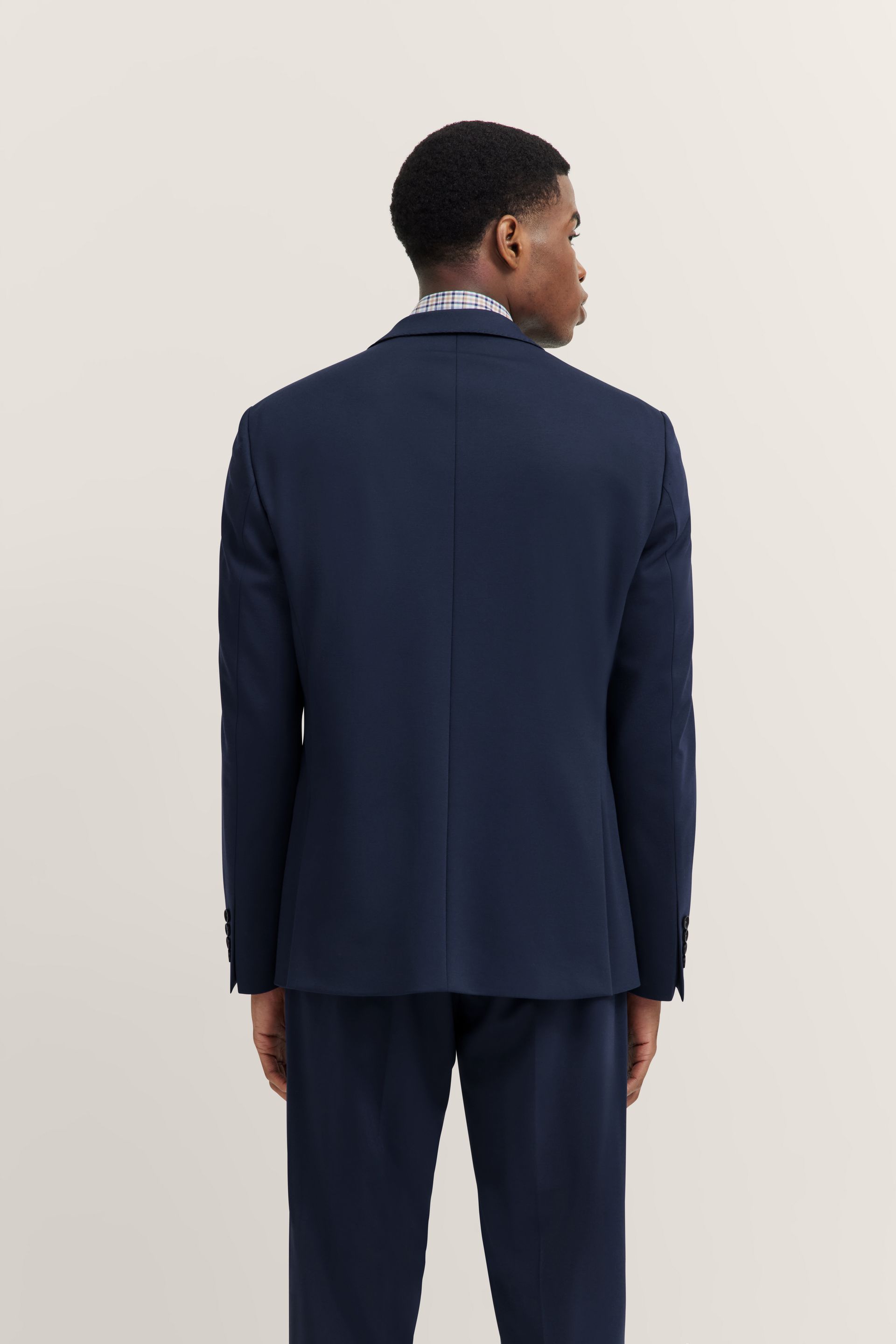 La schiena di un uomo che indossa una giacca e pantaloni blu.