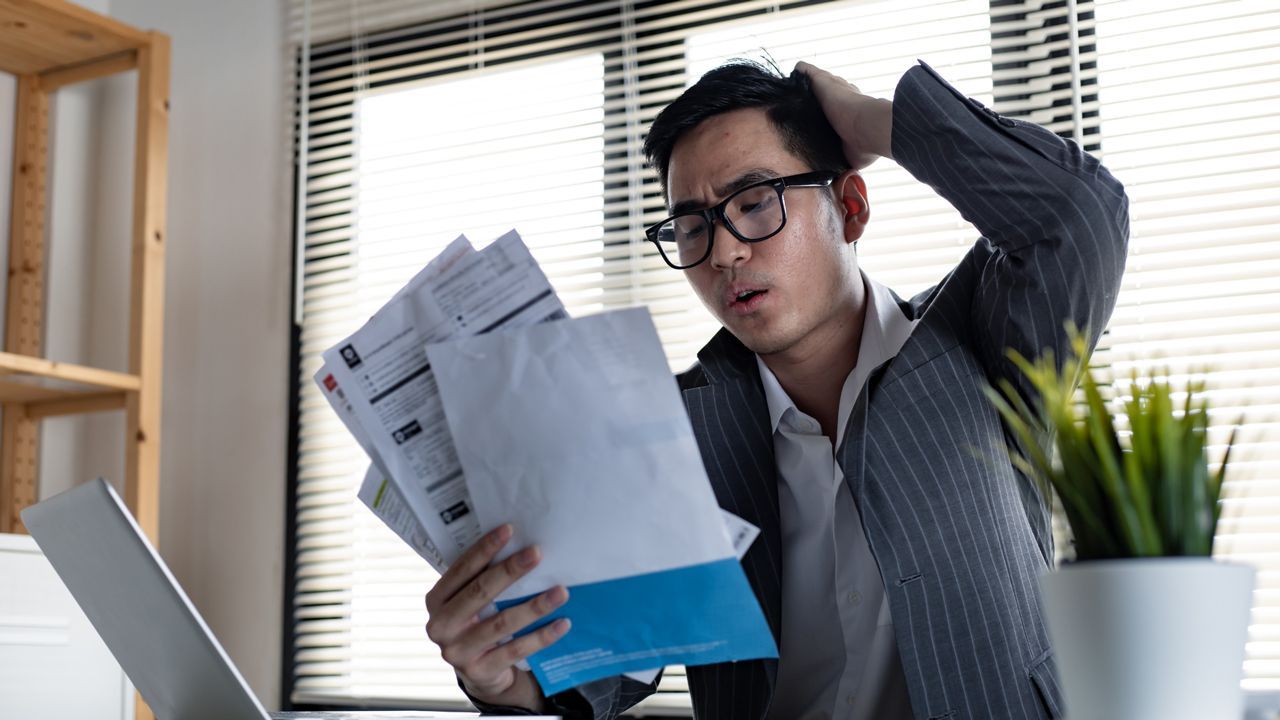 A man is sitting at a desk holding a stack of papers.