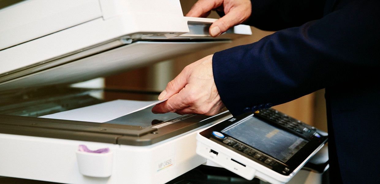 A person is using a copier to scan a piece of paper.
