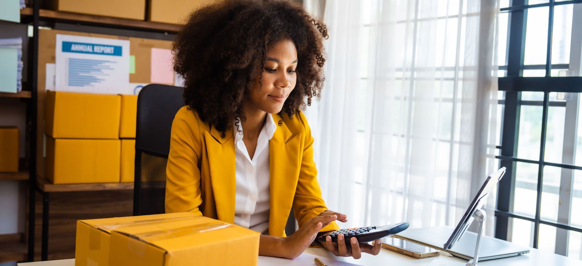 A woman is sitting at a desk using a cell phone.