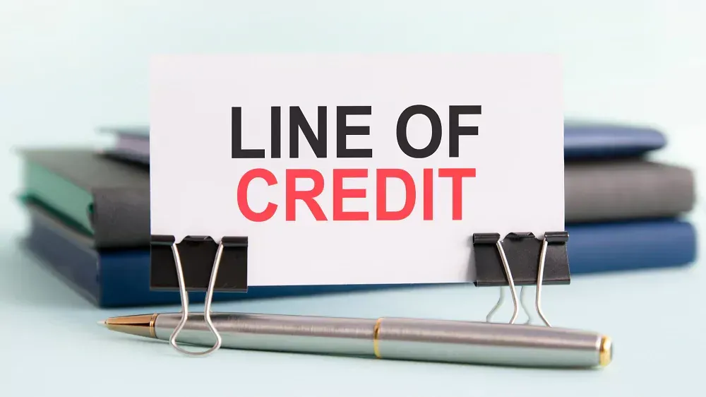 A card with the words `` line of credit '' written on it is sitting on top of a stack of notebooks.