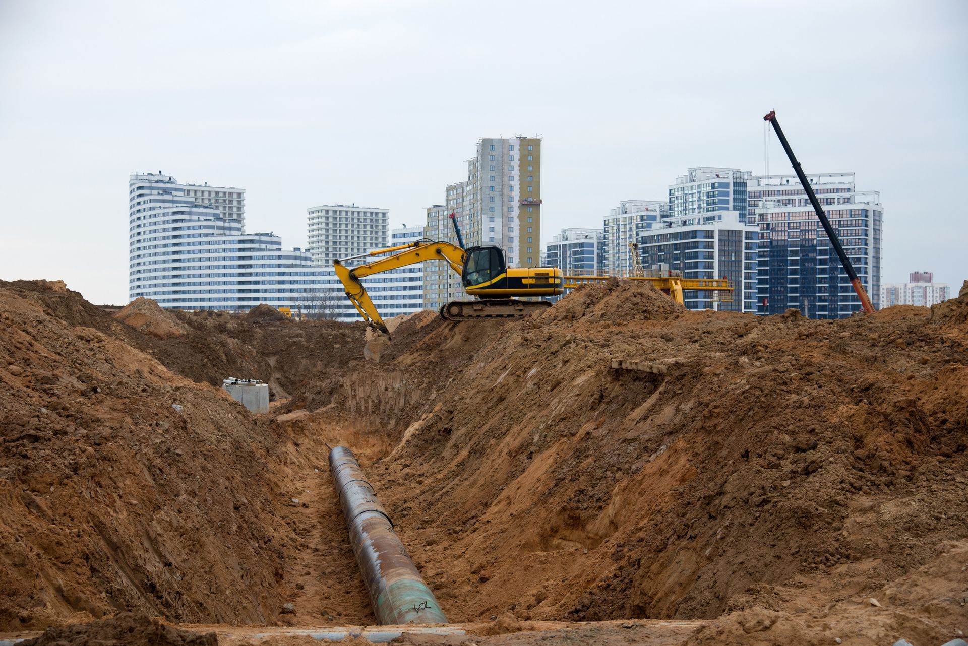 A yellow excavator is digging a hole in the dirt at a construction site.