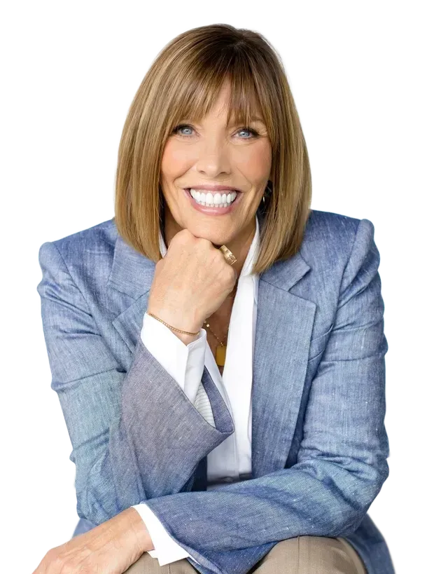 Woman in blue blazer smiles, rests chin on hand.