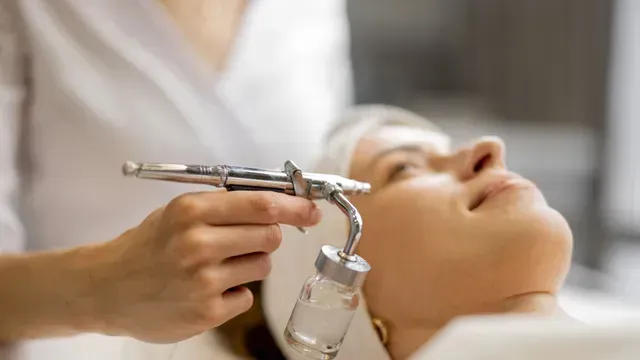 A woman is getting an oxygen treatment on her face.