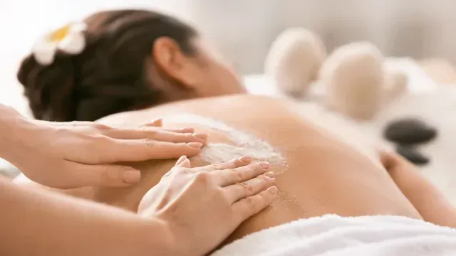 Person receiving a back treatment at a spa; hands applying cream.