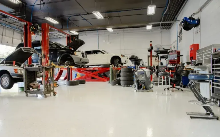Auto repair shop interior with cars on lifts, tires, and tools on a bright workshop floor
