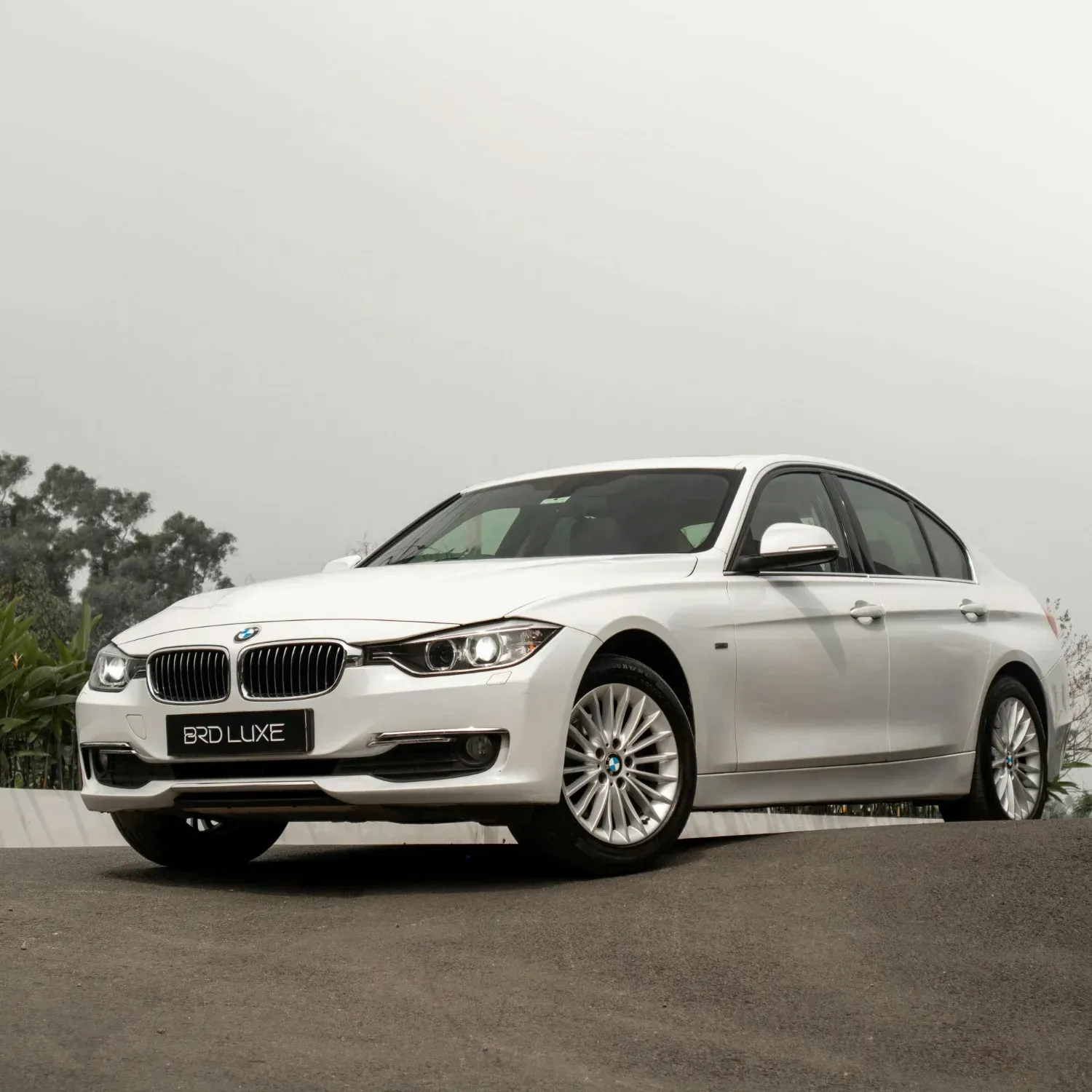 White BMW sedan parked on a road under an overcast sky